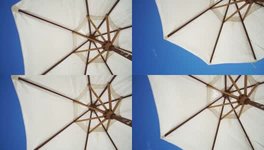 白色沙滩阳伞。避暑伞下夏日明媚的蓝天高清在线视频素材下载