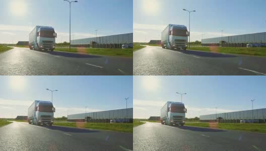大型白色半挂车与货物拖车移动在工业仓库区域的空旷道路与阳光照耀的背景。高清在线视频素材下载