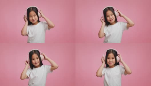 韩国小女孩戴着耳机听音乐在粉红色的背景高清在线视频素材下载