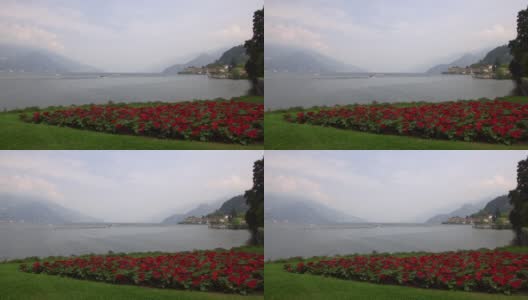 科莫湖岸边的贝拉吉奥岛充满浪漫气息。前景是红色的花朵，背景是云层中的意大利阿尔卑斯山。轻松的气氛。高清在线视频素材下载