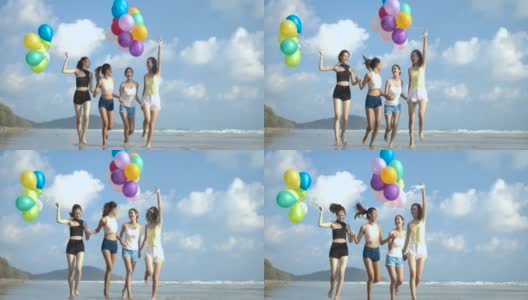 潮人朋友们拿着彩色气球走在海滩上，心情愉快。有聚会庆祝观念的人。4 k决议。慢动作镜头。高清在线视频素材下载