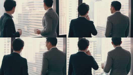 两个商人站在办公室里，一边喝咖啡一边看着窗外和团队成员聊天高清在线视频素材下载