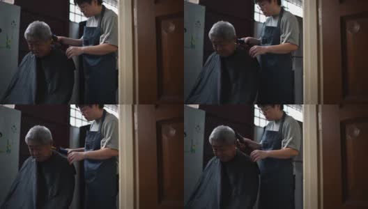 由于旅行禁令，一位亚洲华人中年妇女正在厨房里为她的父亲修剪头发高清在线视频素材下载