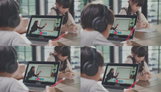 由于冠状病毒大流行，亚洲小男孩通过数字远程互联网会议从学校老师那里学习在线课程。孩子看着电脑笔记本电脑屏幕，那个女人在教书。高清在线视频素材下载