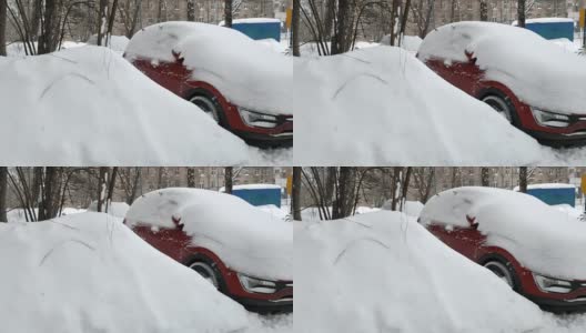 一辆覆盖着厚厚的积雪的红色轿车停在一所积着厚厚的积雪的房子的院子里高清在线视频素材下载
