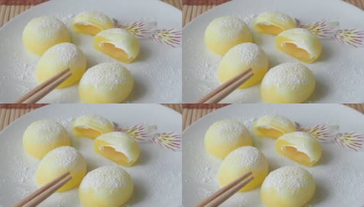 白盘子里的麻糬。黄色的米饭甜点，麻糬大多是日本的传统甜食高清在线视频素材下载