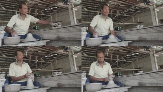 亚洲华人活跃的高级陶工工作在他的工作室与纺陶轮高清在线视频素材下载