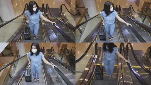 亚洲妇女戴医用口罩，以预防冠状病毒大流行传染病的爆发，并在公共区域乘坐自动扶梯。病毒大流行的概念高清在线视频素材下载