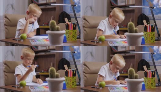 一个小孩子在家做作业，他坐在书桌前写笔记本。高清在线视频素材下载