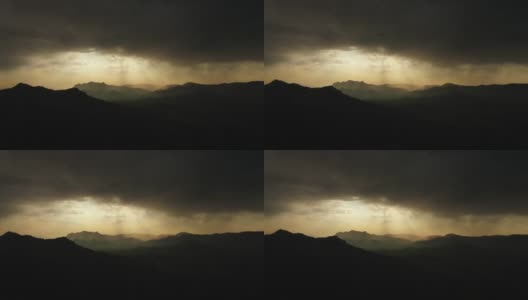 雷暴前的自然山脉全景，令人赏心悦目。从乌云中透出来的明亮阳光照亮了岩石山脉的轮廓高清在线视频素材下载