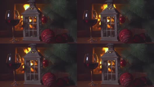 桌上放着一杯红酒，一盏圣诞灯和一棵圣诞树。背景-壁炉与火焰。新年假期酗酒。酒精饮料。火的背景。独自喝。餐厅的饮料高清在线视频素材下载