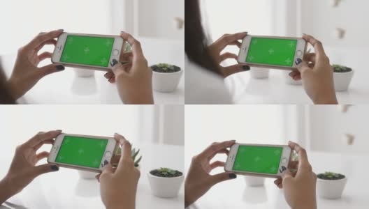 女人的手一边用智能手机，绿色的屏幕一边试图在白色的桌子上捕捉仙人掌，特写-股票视频高清在线视频素材下载
