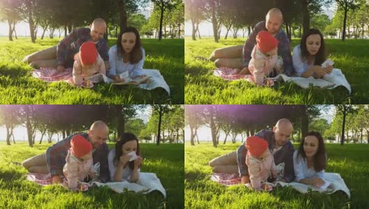 幸福的一家人躺在草地上，和孩子一起在公园里野餐，看一本书高清在线视频素材下载