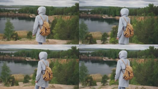 慢动作肖像的年轻女子游客与背包走到悬崖的边缘与湖泊和森林的美丽景色。旅游，人与自然的概念。高清在线视频素材下载