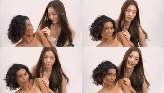 微笑的亚洲美丽的棕褐色和白人妇女与头发运动在白色的背景。人以美容、保健、情感为理念。高清在线视频素材下载