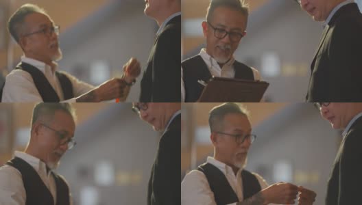 亚洲华人高级男裁缝用卷尺测量他的客户的身体尺寸为新的运动夹克在工作室制作，并写下数字平板电脑记录数字高清在线视频素材下载