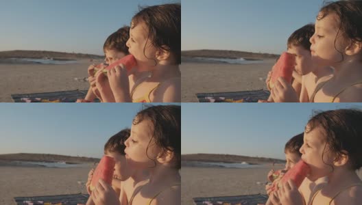 三个孩子在海滩上吃西瓜高清在线视频素材下载