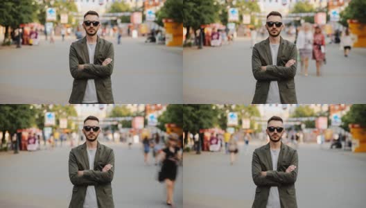 一个戴着太阳眼镜的年轻人站在拥挤的人潮中，在人行道上一动不动高清在线视频素材下载