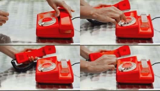 红色古董旋转电话在桌子上，侧面观看。女性的一只手拨通电话，另一只手拿着听筒。高清在线视频素材下载
