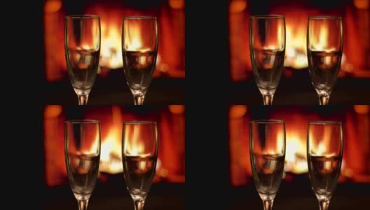 两个空酒杯的特写镜头与舒适温暖的壁炉与火焰在一个黑暗的公寓室内的背景高清在线视频素材下载