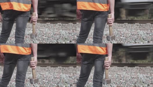 铁路工人拿着一把大锤站在铁路旁边。铁路维护的概念。高清在线视频素材下载
