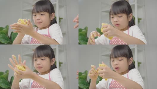 快乐的亚洲孩子在家里一起学习做饼干，女孩在她的手中打面团。高清在线视频素材下载