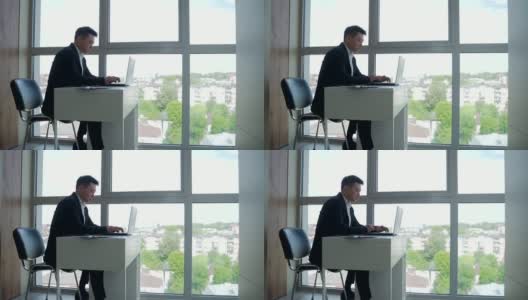 一个亚洲商人坐在办公室的电脑前工作高清在线视频素材下载