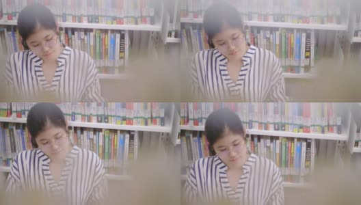 亚洲女孩坐在图书馆看书高清在线视频素材下载