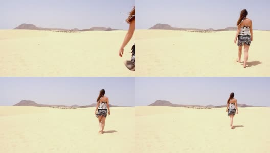 一个孤独的女人在阳光明媚的日子里赤脚走在明亮的黄色沙丘上高清在线视频素材下载