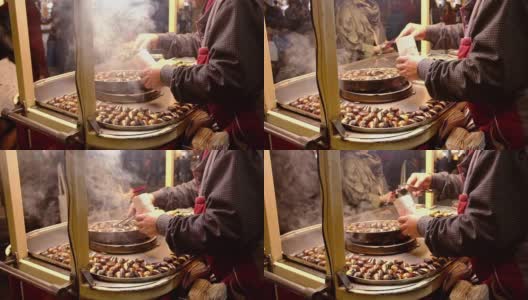 在土耳其的伊斯坦布尔，一名身份不明的土耳其男子在出售带烟的甜栗子。高清在线视频素材下载