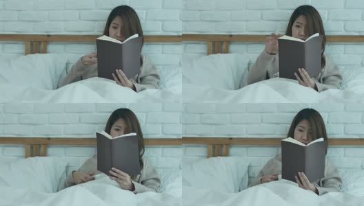 美丽的亚洲女人享受喝温暖的咖啡和看书在床上在她的卧室。亚洲女性穿着舒适的毛衣捧着一本书和一杯咖啡。生活方式亚洲女性在家的概念高清在线视频素材下载