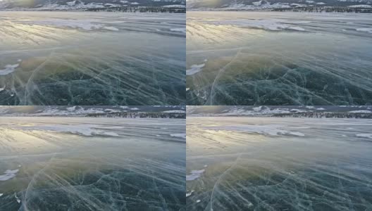 雪在冰面上飞舞。雪花在贝加尔湖的冰面上飞舞。冰非常美丽，有独特的裂缝。背景视图山景。雪花闪耀着红光。高清在线视频素材下载