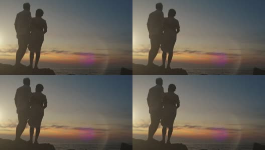 日落时分，一对情侣手牵着手站在岩石上高清在线视频素材下载