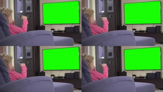 孩子坐在电视机前看儿童节目。绿色色度键屏幕高清在线视频素材下载