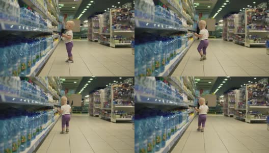 可爱的小孩走在超市的水部，在大市场里挑选瓶子，仔细考虑要买的产品高清在线视频素材下载