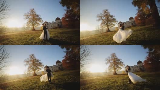 一对夫妇在日落时跳舞。新郎举起新娘，用慢镜头拉近她的镜头高清在线视频素材下载