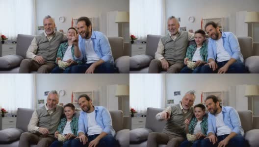 快乐的爷爷，爸爸和儿子在看电视上的喜剧节目，一起玩得很开心高清在线视频素材下载