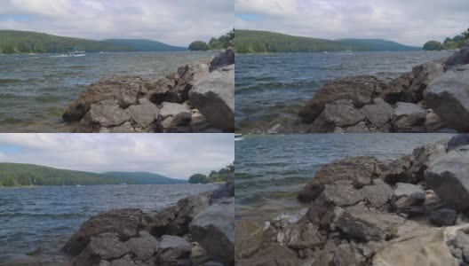 在多云的夏日，海浪拍打着湖附近的岩石高清在线视频素材下载