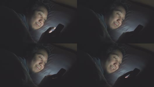 亚洲男人晚上在床上玩智能手机高清在线视频素材下载