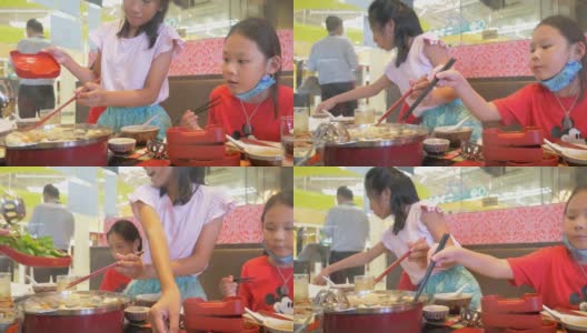 孩子们一起在餐馆吃素琪烧中国菜火锅和蔬菜。高清在线视频素材下载