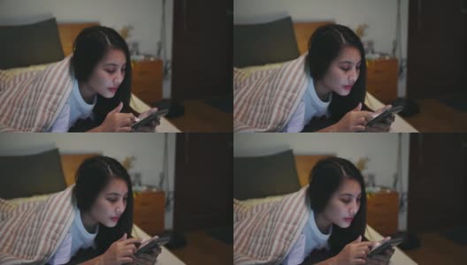 孤独的年轻亚洲女人使用智能手机和社交媒体盖着毯子在卧室高清在线视频素材下载