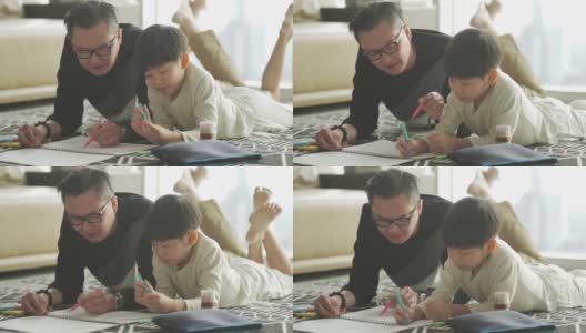 亚洲华人年轻的父亲和儿子周末在家里客厅公寓里画画，享受亲子时光高清在线视频素材下载