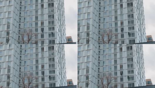 高层建筑商在一幢摩天大楼外立面上进行建筑维修高清在线视频素材下载