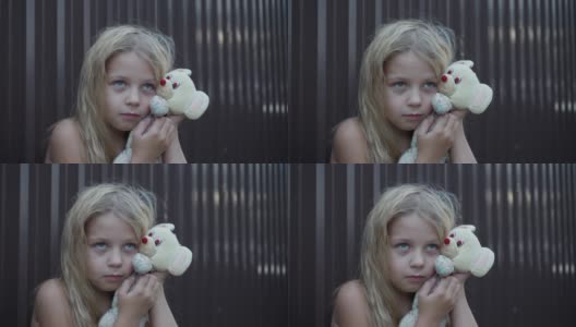 一个不整洁的女孩脸上的表情，手里拿着一个简单的玩具。蓬乱的头发和孩子的悲伤表情。高清在线视频素材下载