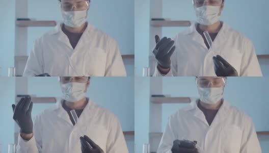 医生穿着晨衣，戴着防护橡胶手套，戴着护目镜，在近距离观察瓶中的液体是否有异味。科学实验室的研究工作。高清在线视频素材下载