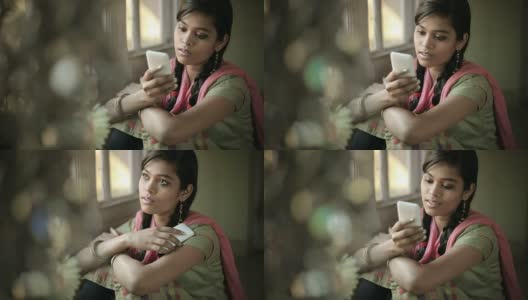 美丽安详的印度女孩坐在窗边读短信。高清在线视频素材下载