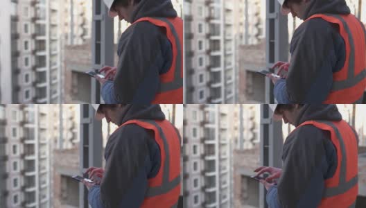 一个建筑工地的建筑工程师在用智能手机工作。高清在线视频素材下载