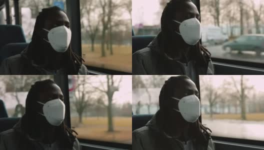 画像靠近车窗的黑人男子在公交车上戴着面罩，正对着乘客的脸高清在线视频素材下载