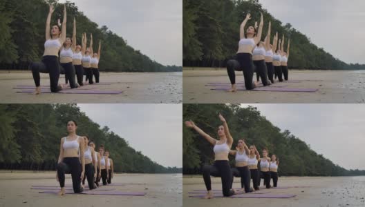 沙滩瑜伽组，女子在沙滩上排队练习瑜伽，女子团队健康生活方式高清在线视频素材下载