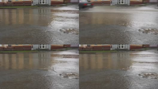 雨水落在路上，流过下水道。汽车在被水淹没的道路上行驶。高清在线视频素材下载